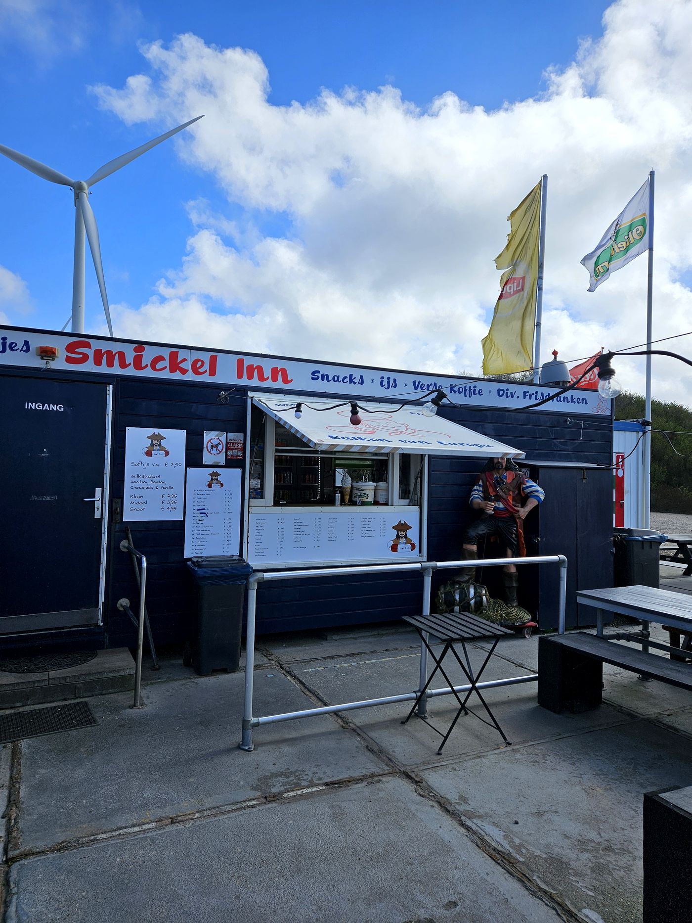 De gevel van snackbar Smickel Inn op de Maasvlakte, met een piratenbeeld bij de ingang en een windmolen erboven