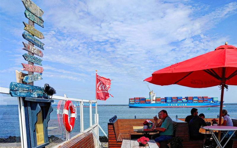 Terras van snackbar Smickel Inn op de Maasvlakte met uitzicht op een passerend containerschip