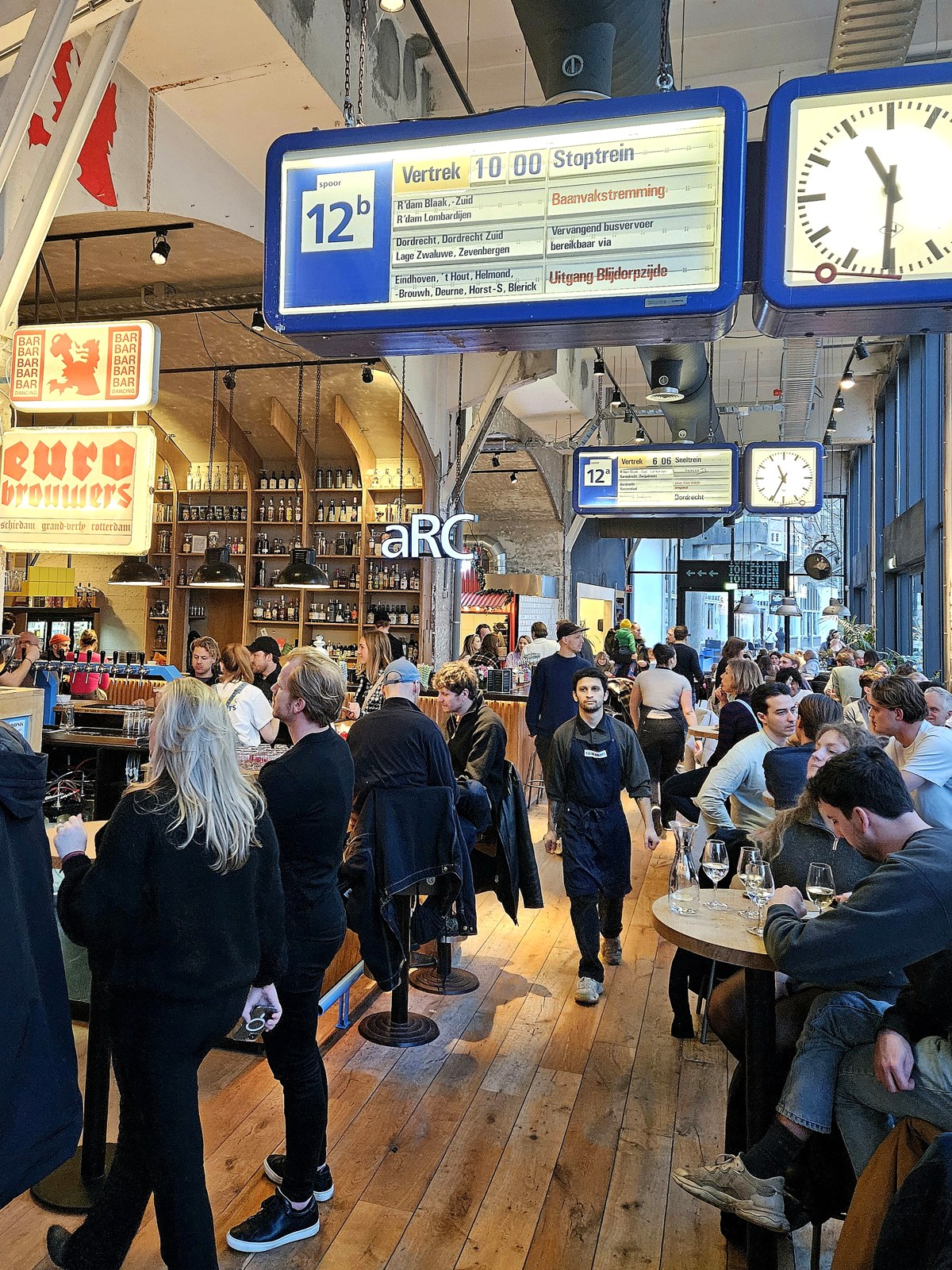 De foodhal van Station Bergweg met de oude vertrekborden en stationsklokken aan het plafond