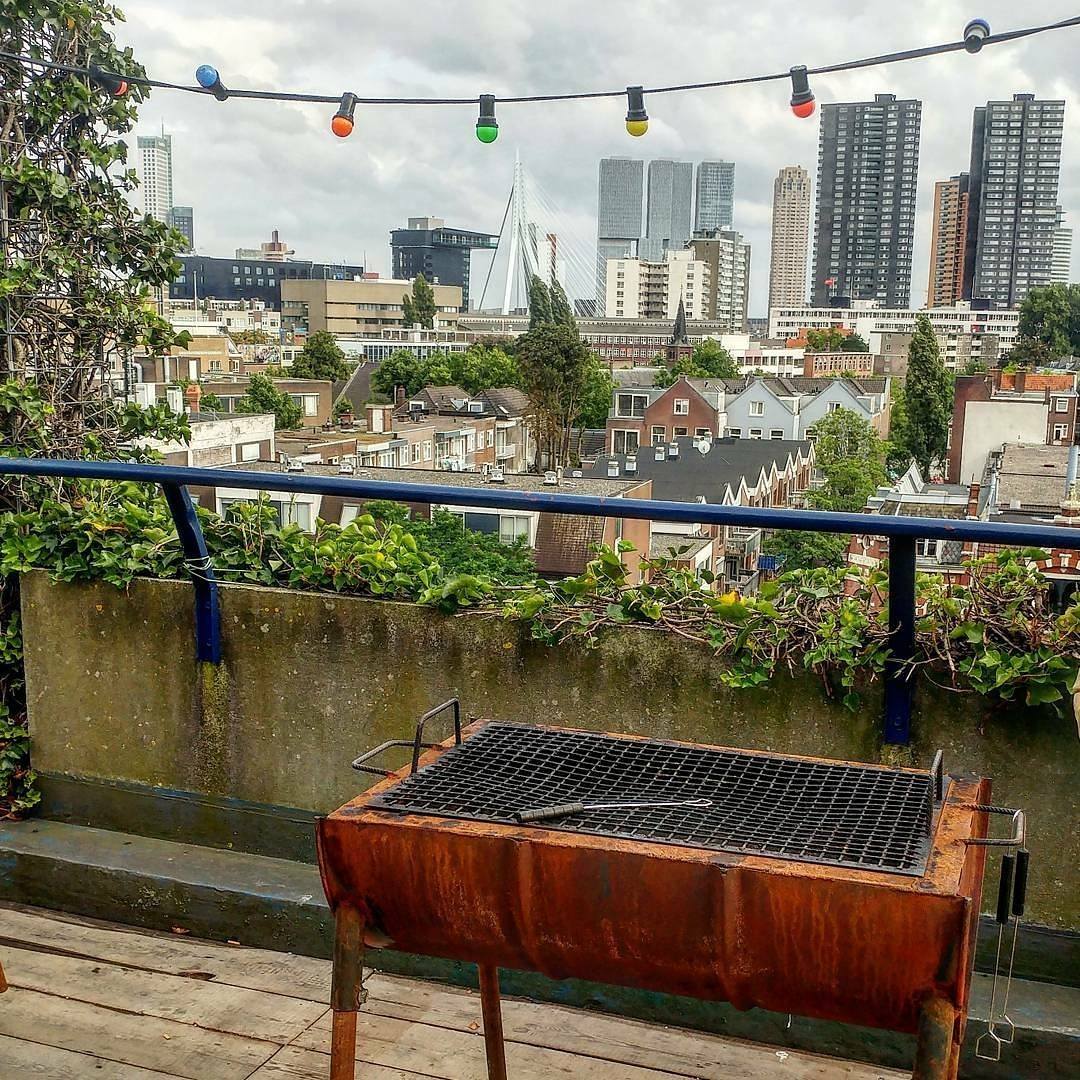 Een lege, schoongemaakte bbq-grill op het dak met uitzicht over de Rotterdamse skyline