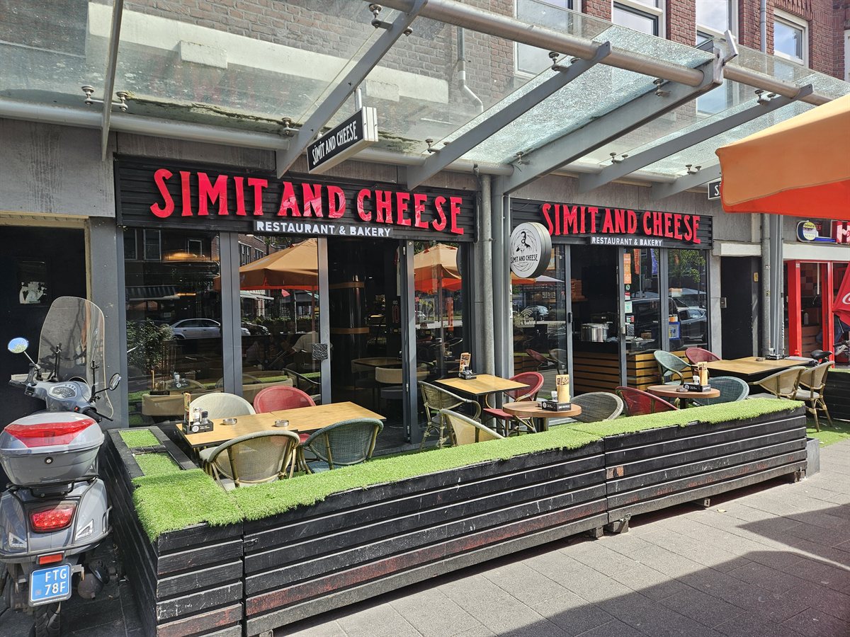 De gevel van Simit and Cheese aan de Beijerlandselaan, met een zonnig terras ervoor.