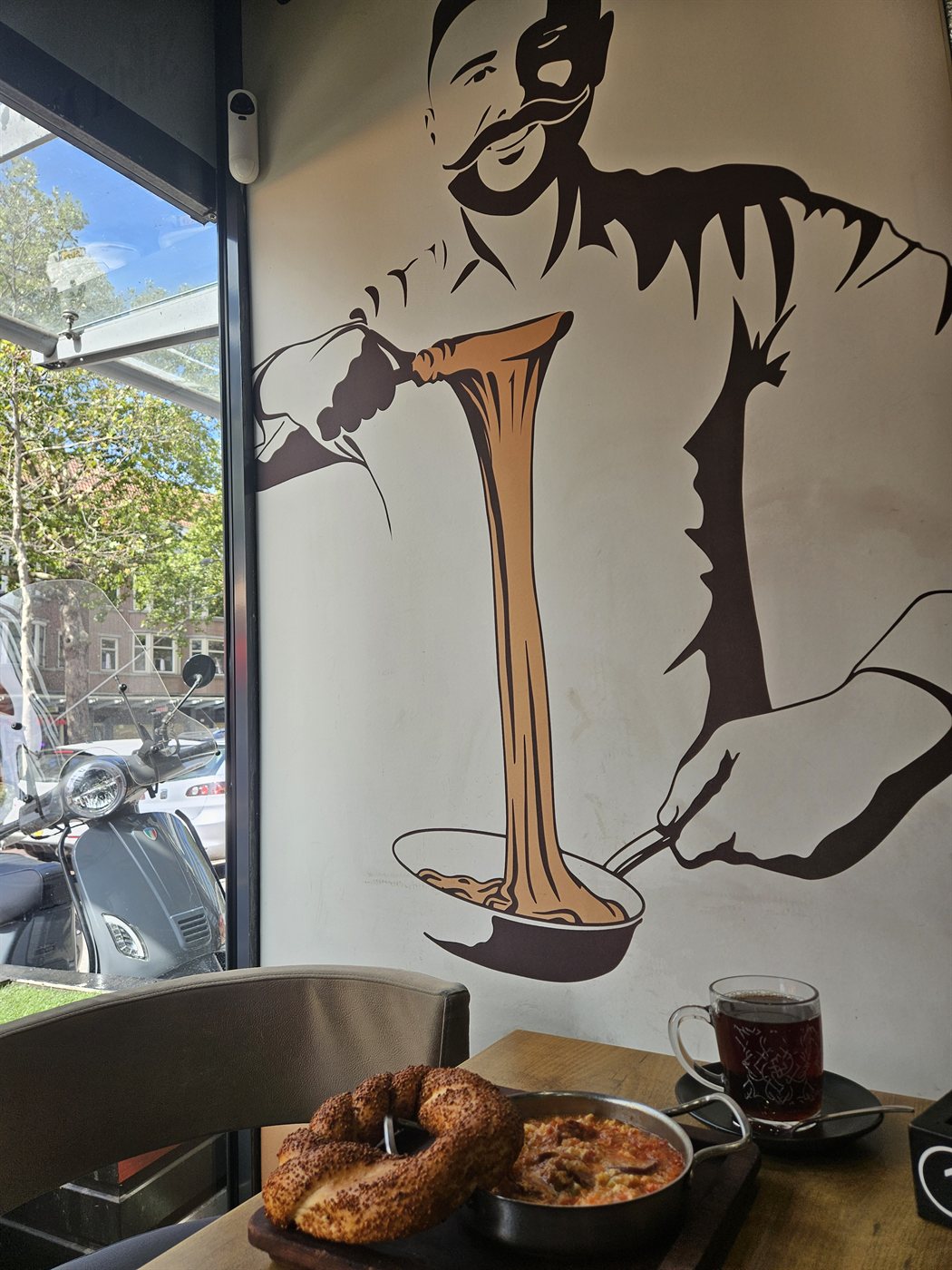 Een muurschildering bij Simit and Cheese van de bekende kuymak-kaasfondue die aan een simit wordt gedipt.