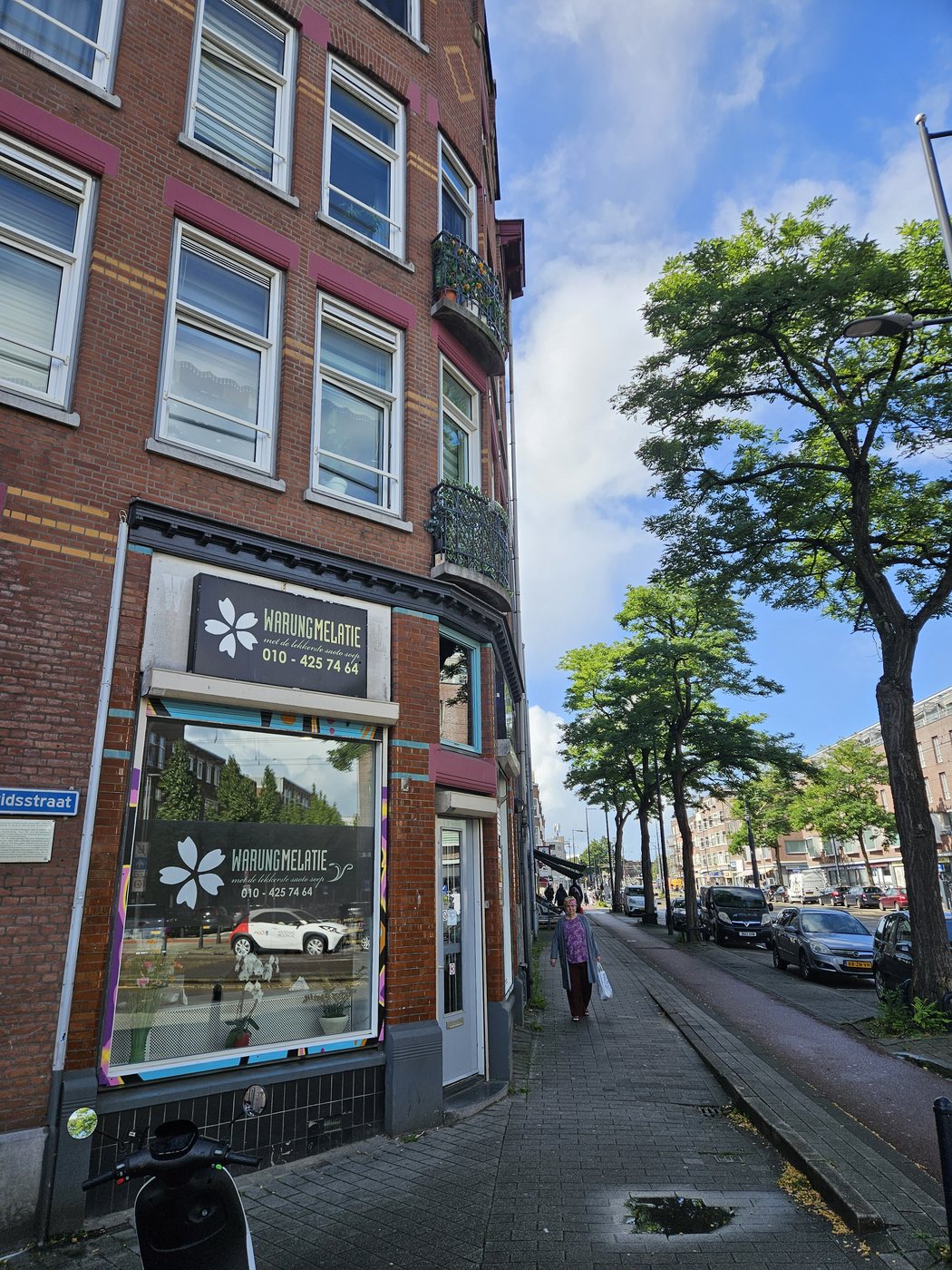 De hoekgevel van Warung Melatie aan de Vierambachtsstraat, met het logo en telefoonnummer boven het raam.